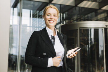 confident-smiling-young-woman-holding-mobile-phone-hand