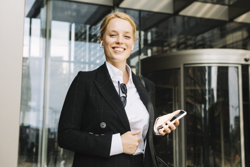 confident-smiling-young-woman-holding-mobile-phone-hand